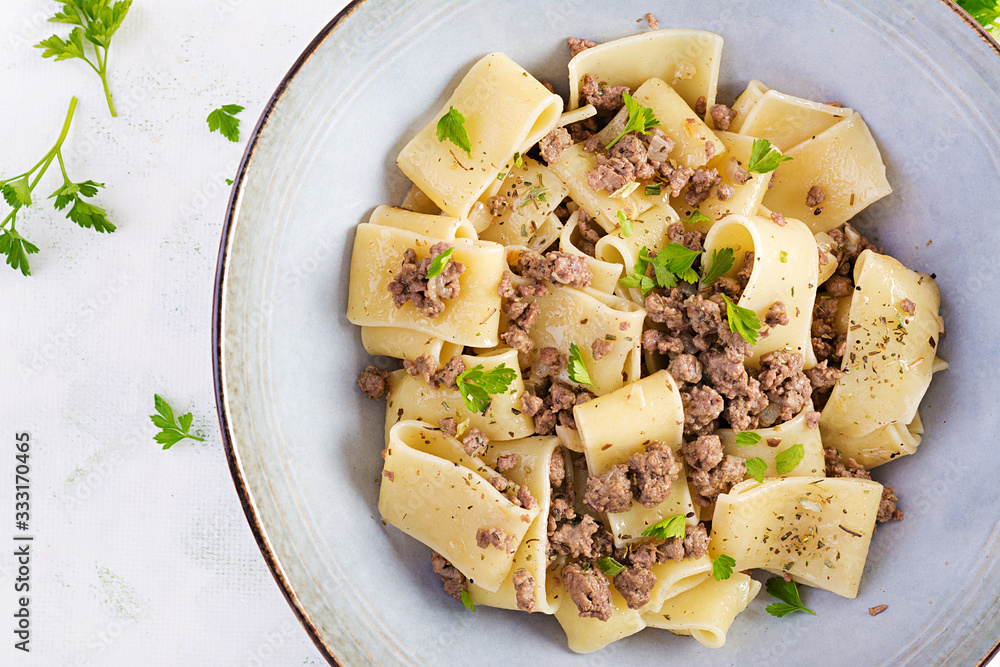Pasta Calamarata with minced meat in blue bowl. Italian cuisine. Top view, overhead Pasta Calamarata with minced meat in blue bowl. Italian cuisine. Top view, overhead