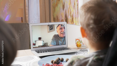 Family talking with parents on facetime video chat. Children communicating with their grandfather on webcam. Modern technology connecting people of all ages concept. 