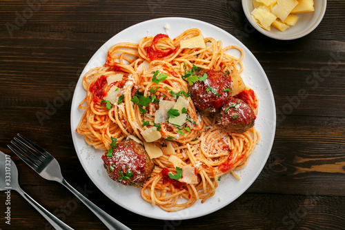Italian meal made of pasta on a wooden table. Plate of traditional American spaghetti with meatballs and tomato sauce. Top view shot directly above.