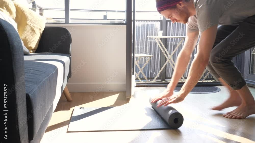 Barefoot Yoga Man Rolls Up Yoga Mat at Home After Work Out Barefoot Yoga Man Rolls Up Yoga Mat at Home After Work Out