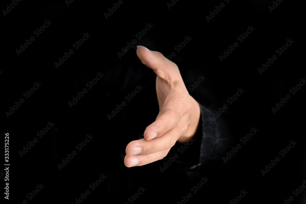 Businessman offer hand for handshake and cooperation over black background. Business deal proposal concept. Businessman offer hand for handshake and cooperation over black background. Business deal proposal concept.
