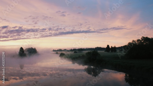 Foggy sunrise landscape with cloud and forest reflection in a river