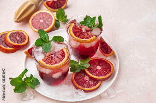 red blood orange cocktail with ice and fresh mint  top view  pink  background