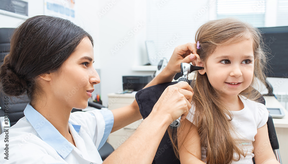 Pediatrician examining little patient with otoscope, hearing exam of child Pediatrician examining little patient with otoscope, hearing exam of child