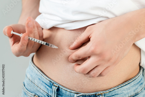 Cropped view of man doing hormonal injection in belly isolated on grey