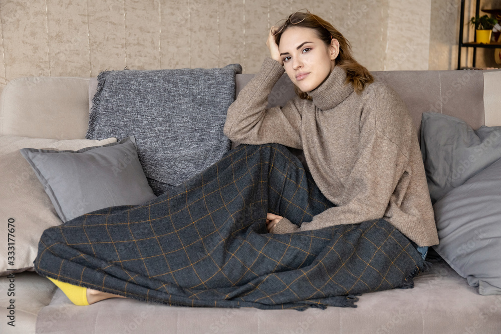 young cute girl misses on the couch under the plaid at home and looks away young cute girl misses on the couch under the plaid at home and looks away