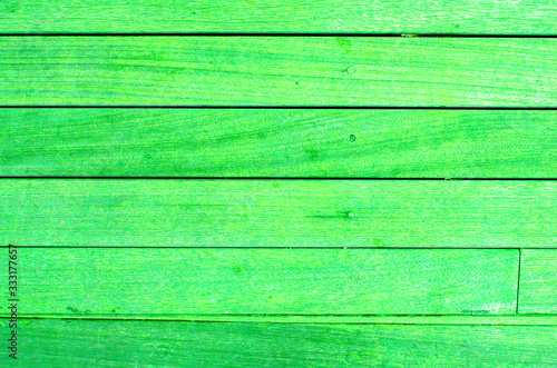 Bright green wooden backdrop, boards. green tinted wood. Fragment of fence, floor or wall of building made of wooden boards, place for text. Copy space.