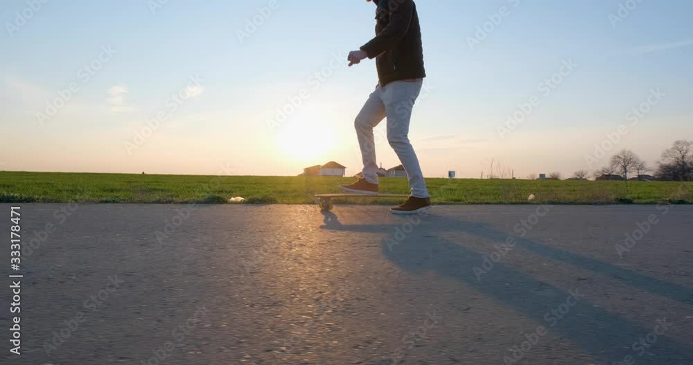Young male ride on skateboard on the empty road during beautiful sunset Young male ride on skateboard on the empty road during beautiful sunset