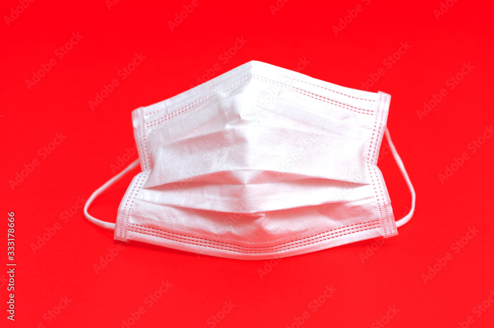 White surgical mask for protection against Coronavirus COVID-19 (SARS-CoV-2) and other contagious diseases. Close-up. Horizontal shot. Isolated on red background. White surgical mask for protection against Coronavirus COVID-19 (SARS-CoV-2) and other contagious diseases. Close-up. Horizontal shot. Isolated on red background.