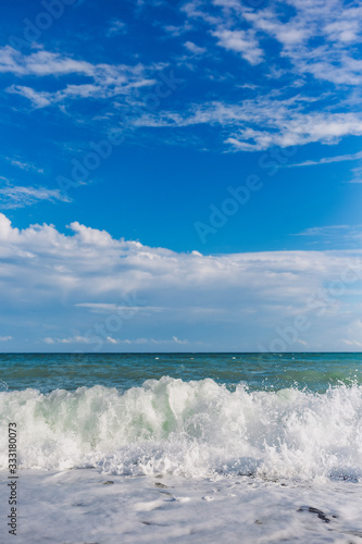 Vertical photography of beautiful summer beach landscape. Splashing sea waves at Turkish beach and clear blue sky with soft peaceful clouds.