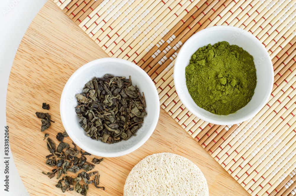 Dry green tea leaves and matcha powder in the small white bowls. Natural beauty treatment, skip-care or zero waste concept. Top view, copy space. Dry green tea leaves and matcha powder in the small white bowls. Natural beauty treatment, skip-care or zero waste concept. Top view, copy space.