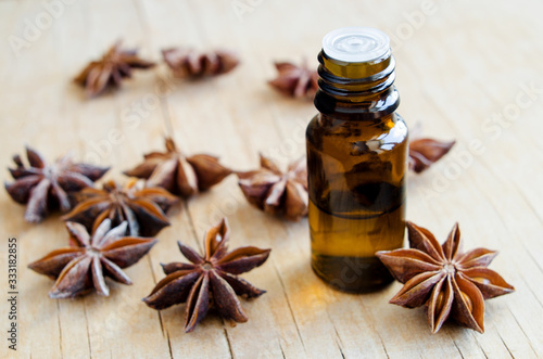 Small bottle with star anise essential oil. Aromatherapy, herbal medicine and spa ingredients. Wooden background. Copy space.