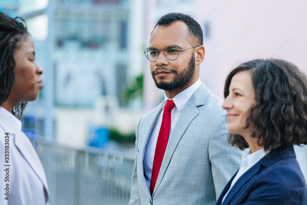 Business partners discussing contract outside. Multiethnic business man and women standing in city street and talking. Meeting outside concept Business partners discussing contract outside. Multiethnic business man and women standing in city street and talking. Meeting outside concept