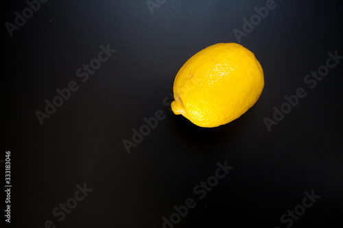 Yellow lemon on black table, food background