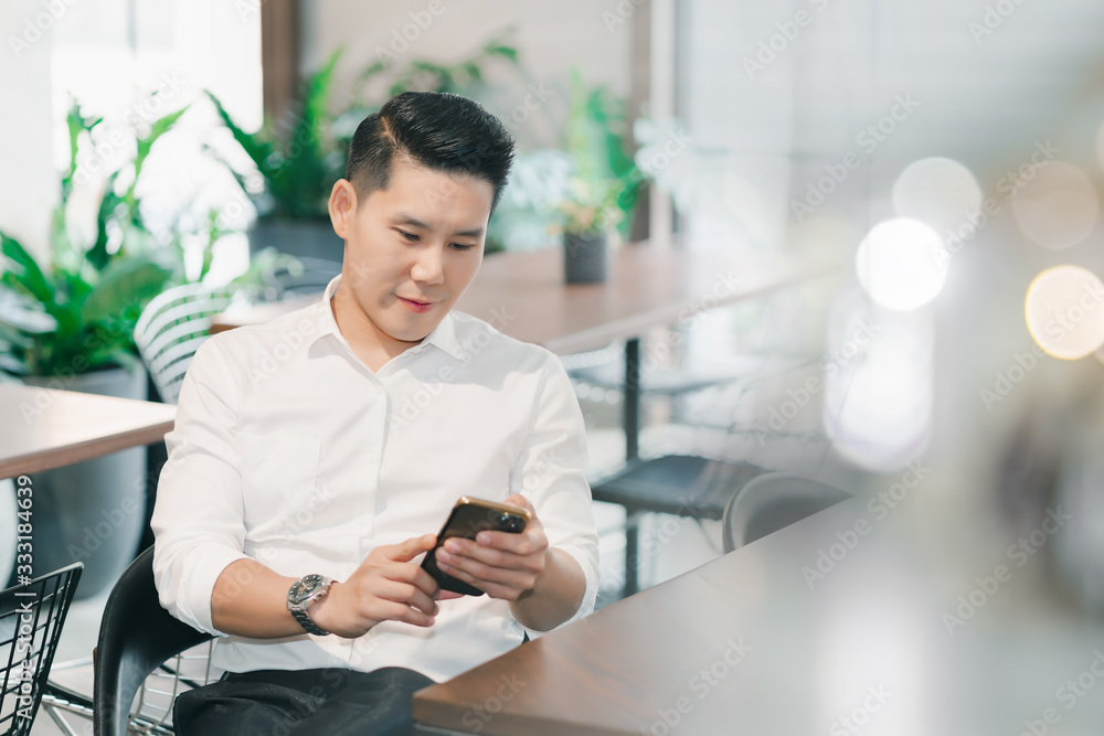 Fototapeta premium business asian man lifestyle in workplace office. smart male asian holding smart phone social distance online.
