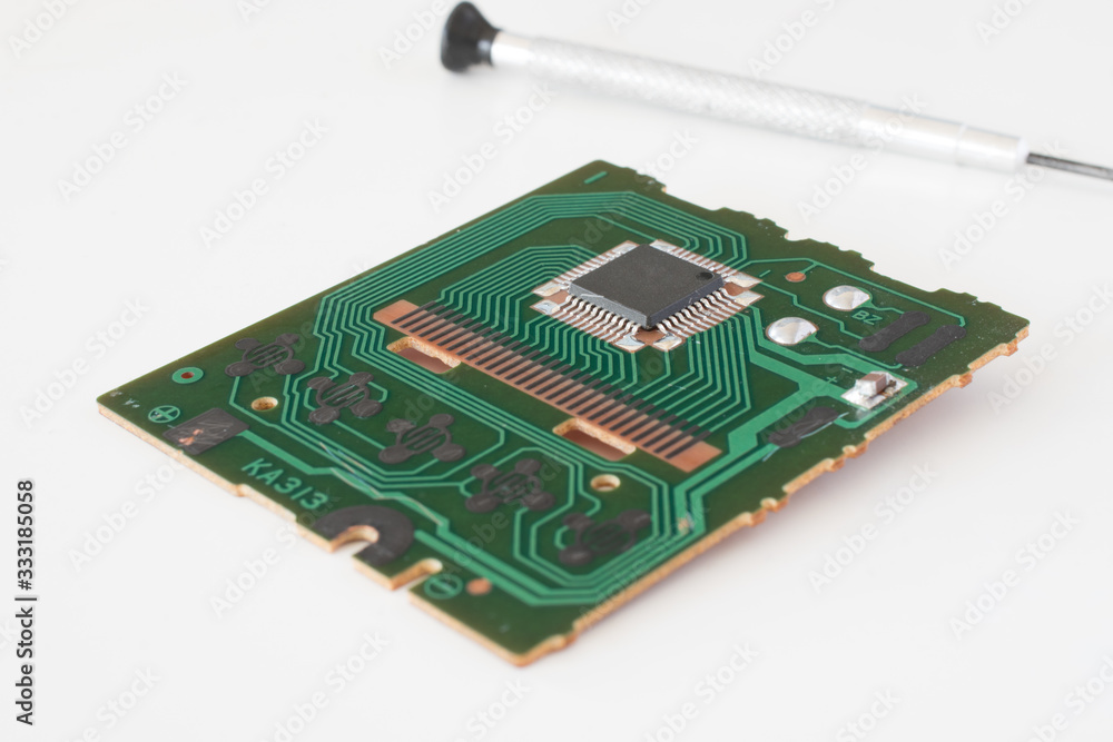 Old circuit with one microchip and a screwdriver in the back. Old circuit with one microchip and a screwdriver in the back.