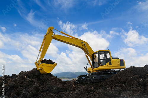 Yellow excavators are digging the soil in the construction site on the blue sky background