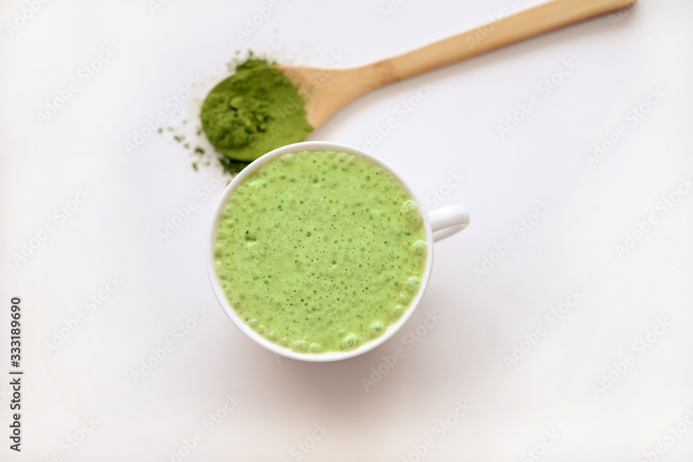 matcha latte in a cup and matcha powder in wooden spoon. healthy drinks concept. modern fashionable drink for weight loss and energy boost. top view matcha latte in a cup and matcha powder in wooden spoon. healthy drinks concept. modern fashionable drink for weight loss and energy boost. top view