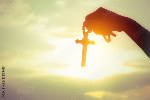 Fotografija Easter Sunday Celebration Concept : Soft focus silhouette of a young woman with a cross or religious symbol above the sky at sunset to celebrate the resurrection of Jesus Christ