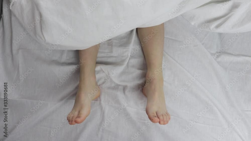 naked beautiful legs under the blanket. one leg scratched the other while sleeping. naked beautiful legs under the blanket. one leg scratched the other while sleeping.