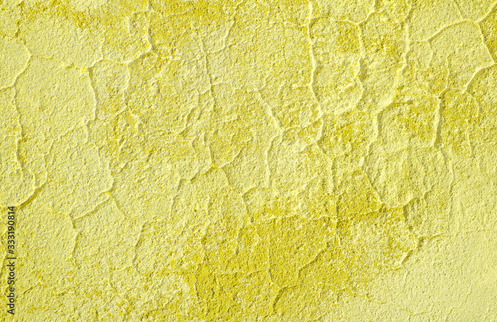 Fototapeta premium Fragment of old house wall close-up. Yellow background. Peeling plaster on concrete surface. Cracks in paint. tinted in yellow, warm colors backdrop. Copy space. Place for text. Selective focus image.