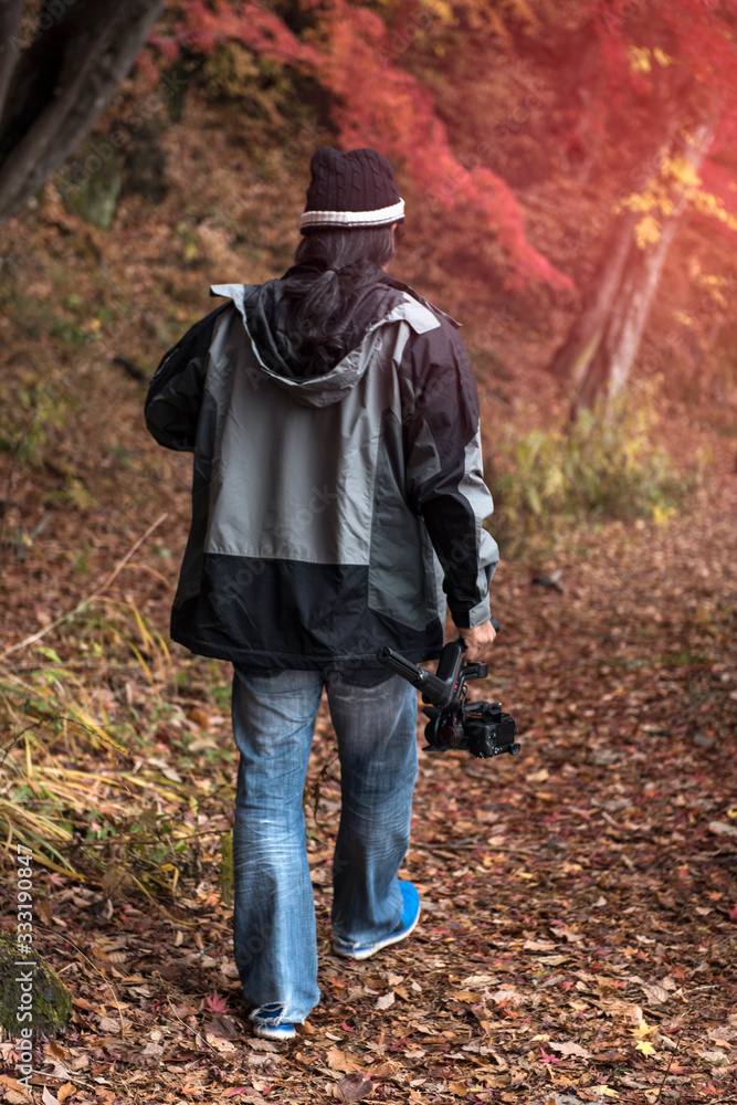 man with camera walking into the forest