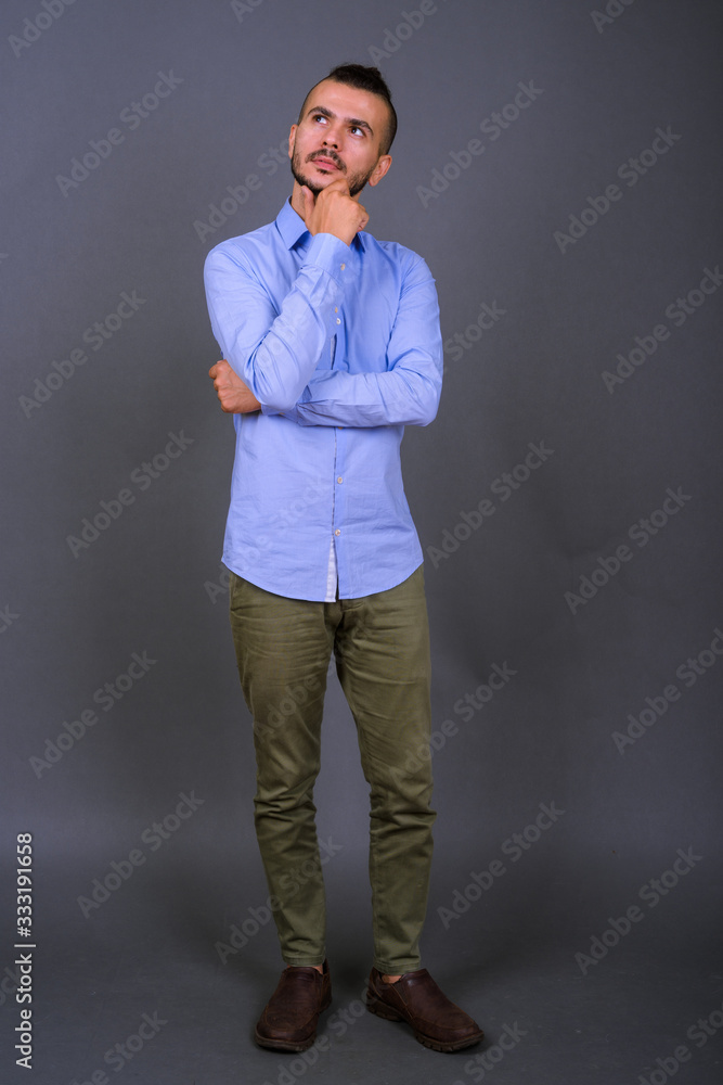 Obraz premium Full body shot of handsome bearded Turkish businessman thinking