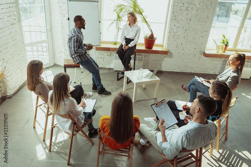 Live briefing. Female speaker giving presentation in hall at workshop. Business centre. Rear view of participants in audience. Conference event, training. Education, diversity, inclusive concept.