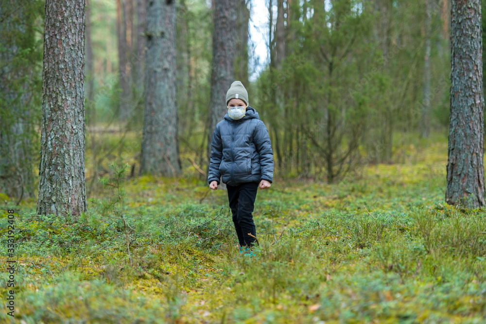Disappointed lonely kid wearing mask for protection of corona virus spread on a empty forest. Disappointed lonely kid wearing mask for protection of corona virus spread on a empty forest.