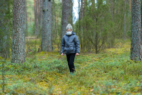 Disappointed lonely kid wearing mask for protection of corona virus spread on a empty forest. © Augustas Cetkauskas