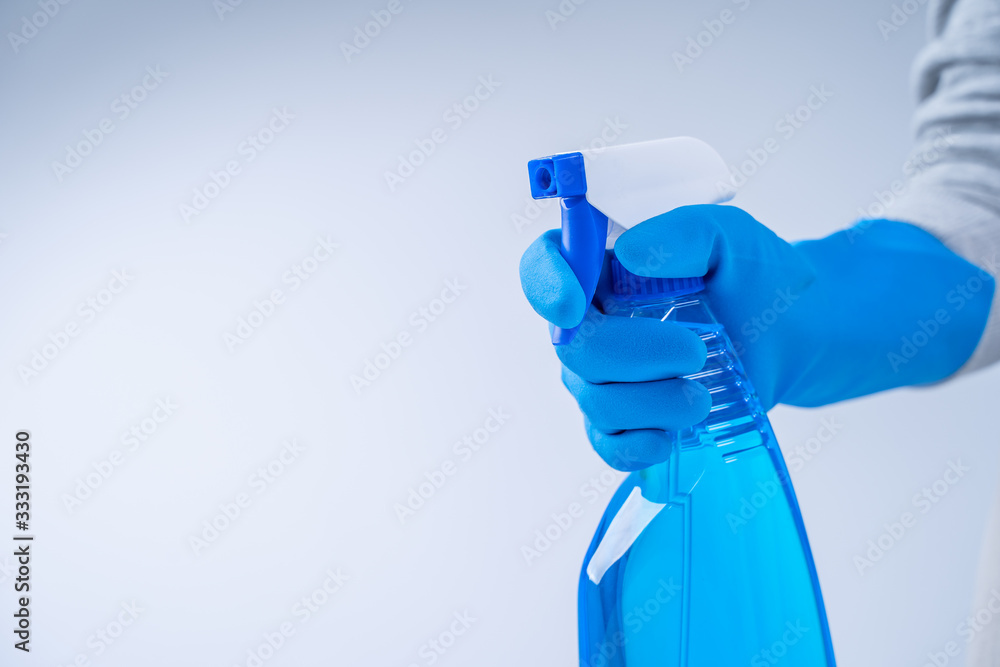 Young woman housekeeper in apron is doing cleaning with blue gloves, wet yellow rag, spraying bottle cleaner, close up, copy space, blank design concept. Young woman housekeeper in apron is doing cleaning with blue gloves, wet yellow rag, spraying bottle cleaner, close up, copy space, blank design concept.