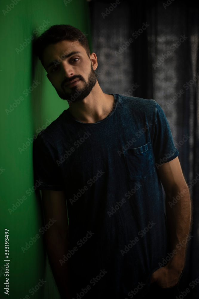Portrait of young brunette Indian  man in casual tee shirt in black background. lifestyle and fashion.