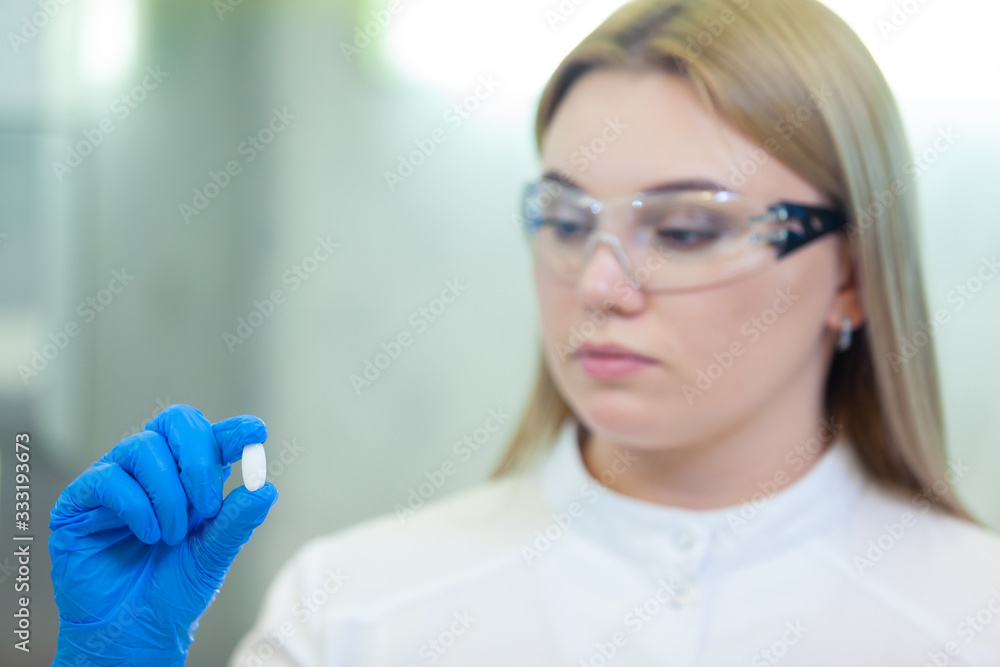 Technician holding a pill. Scientists create new drugs and vaccines in a modern scientific laboratory. Technician holding a pill. Scientists create new drugs and vaccines in a modern scientific laboratory.