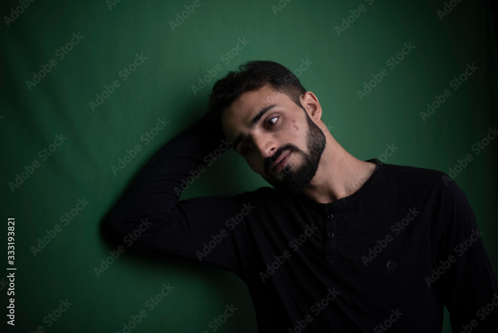 Portrait of young brunette Indian Kashmiri man in casual tee shirt in green copy space studio background. lifestyle and fashion.