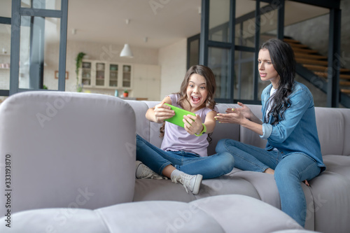 Girl in jeans showing something on a smartphoen to her mom