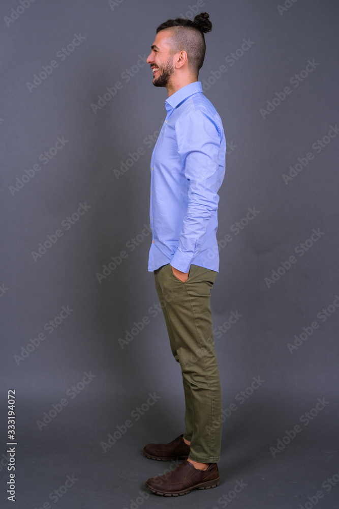 Full body shot profile view of happy bearded Turkish businessman smiling Full body shot profile view of happy bearded Turkish businessman smiling