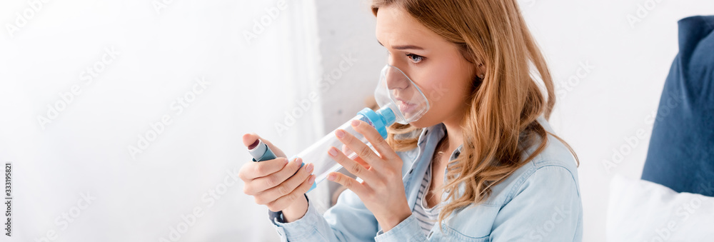 Fototapeta premium panoramic shot of asthmatic woman using inhaler with spacer
