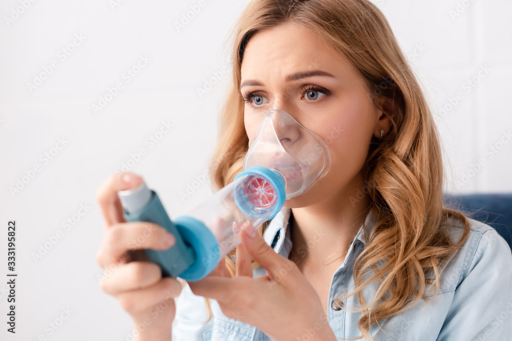 selective focus of asthmatic woman using inhaler with spacer selective focus of asthmatic woman using inhaler with spacer