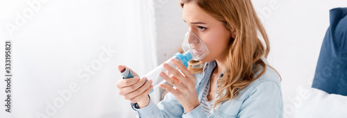 panoramic shot of asthmatic woman using inhaler with spacer photo