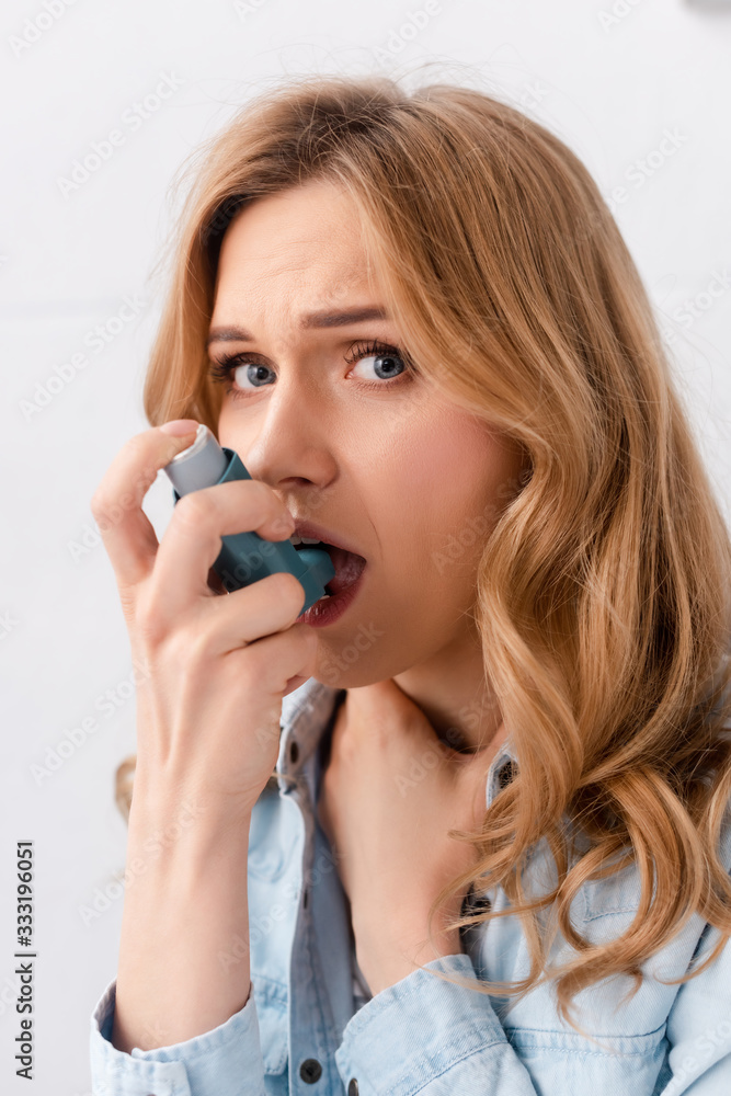 beautiful and asthmatic woman using inhaler and looking at camera beautiful and asthmatic woman using inhaler and looking at camera