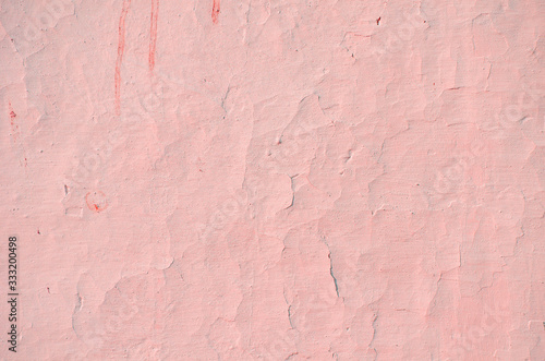 Fragment of old house wall close-up. Pink background. Peeling plaster on concrete surface. Cracks in paint. Copy space. Place for text. Selective focus image.