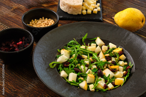 Arugula Salad with Pear on a black plate with ingredients