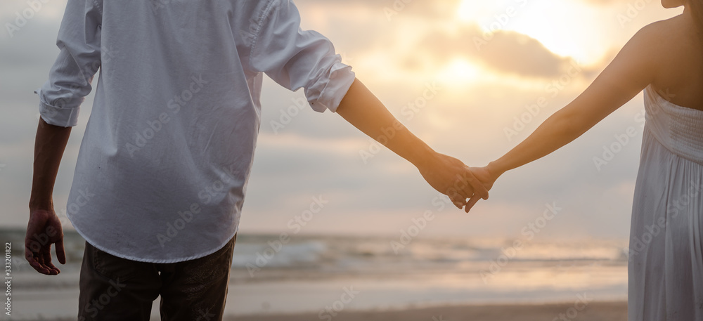 Rear view of couple standing holding hands each other while at beach at sunrise, plan life at future concept. couple, lover, beach, romantic, summer, lifestyle concept.
