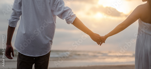 Rear view of couple standing holding hands each other while at beach at sunrise, plan life at future concept. couple, lover, beach, romantic, summer, lifestyle concept. © Day Of Victory Stu.