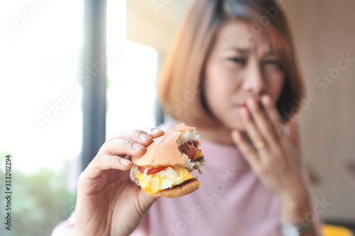 A girl was fulled after eating burger Burger is hight calories food Unpalatable food makes eating less Selective focus