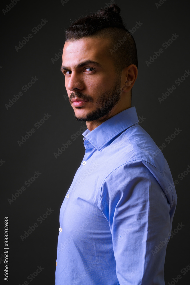 Obraz premium Profile view of handsome bearded Turkish businessman looking at camera