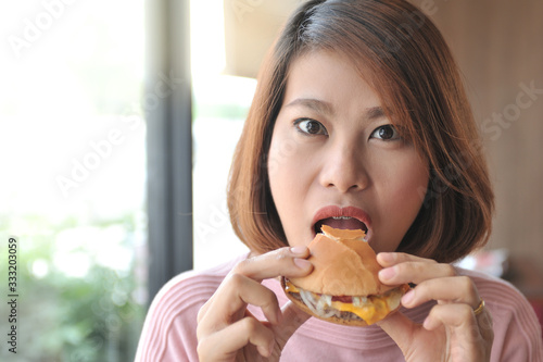 Asian women open her mouth for biting burger,A women enjoy eating with her burger in hands,Selective focus