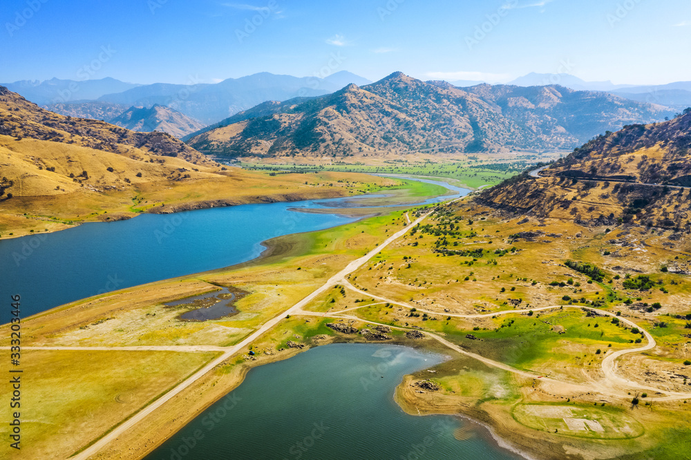 Aerial view top of Lake Kaweah Recreation Area outside of Sequoia National Park. Dry green grass, blue sky, yellow mountains, morning, blue water. Autumn. California, USA 