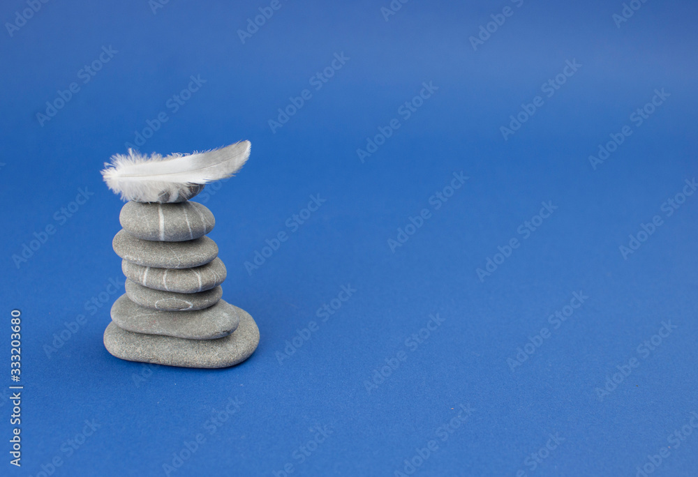 Fototapeta premium Pyramid of stones with feather on the top. Balance concept