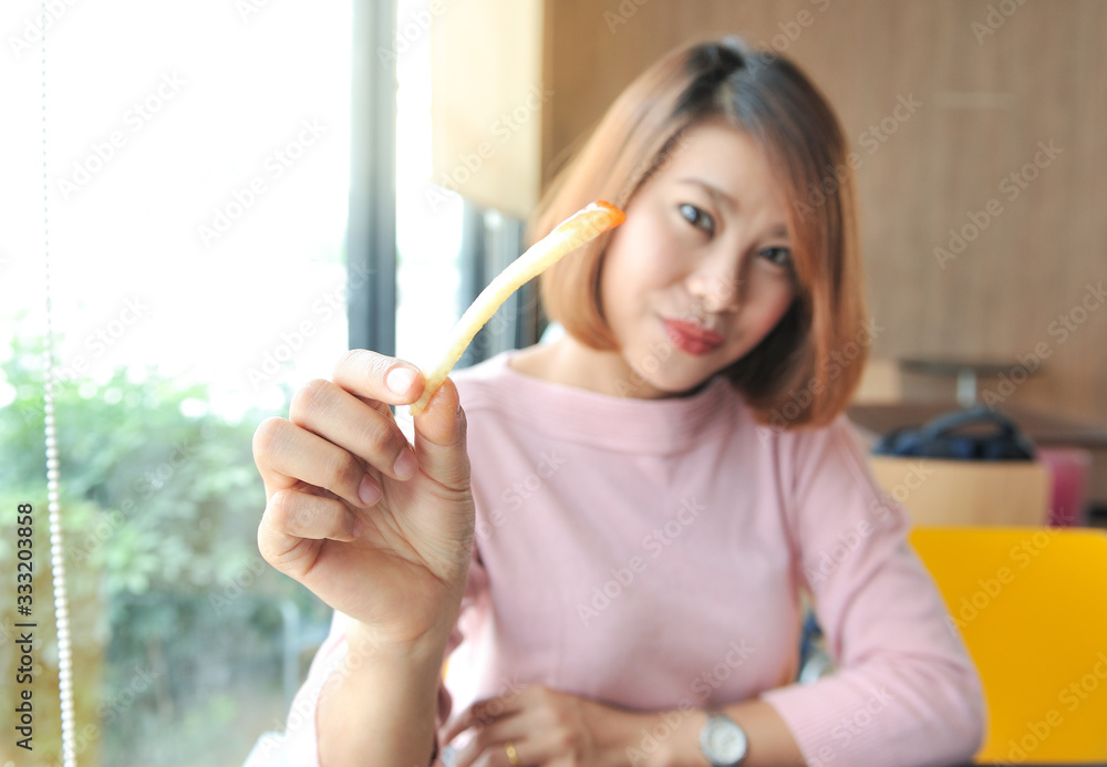 The woman is smiling and holding the French Fries,Happy with meal,Selective focus The woman is smiling and holding the French Fries,Happy with meal,Selective focus